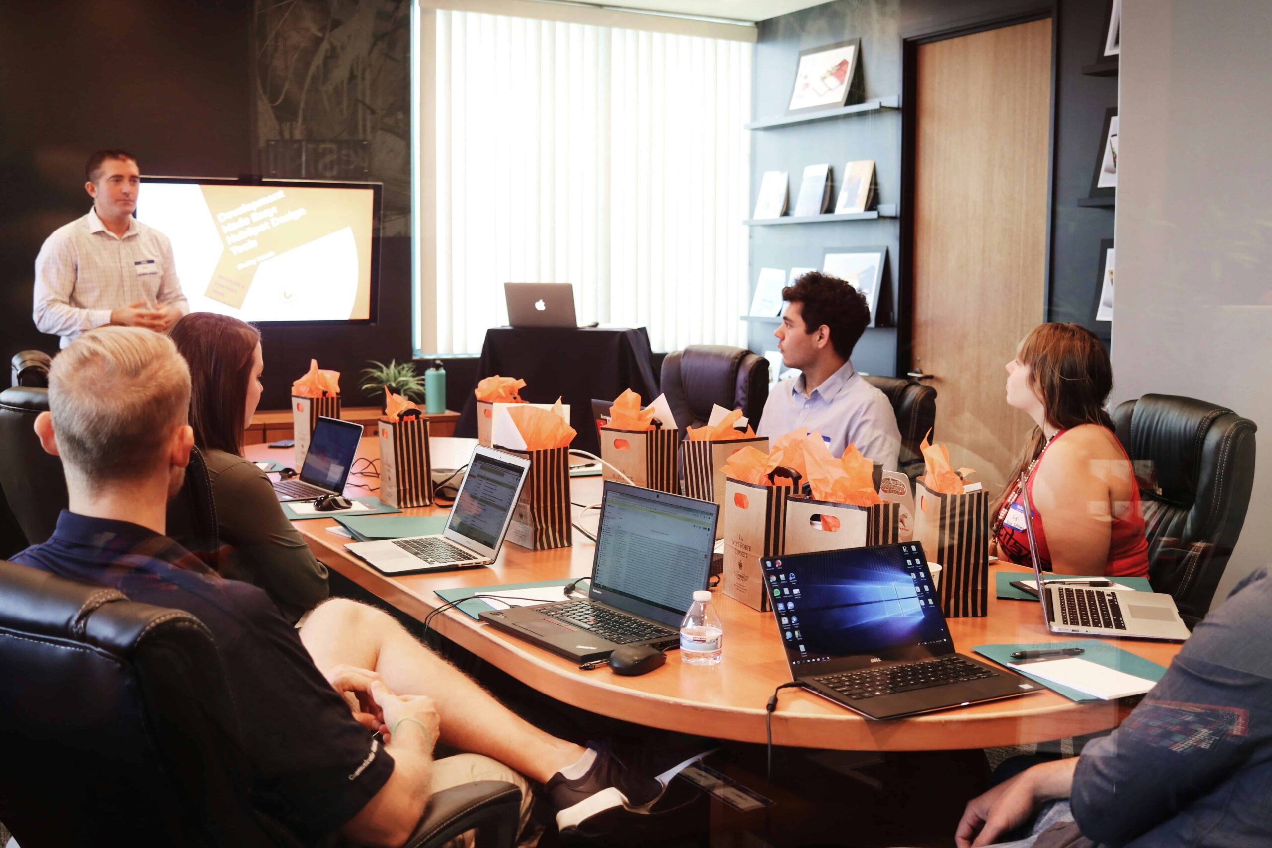 Team attending an HR Management Training session in a modern conference room with laptops and presentation screen.